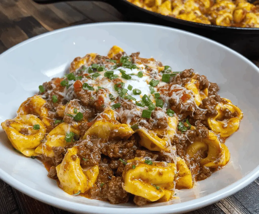 Delicious Beef Enchilada Tortellini served with melted cheese and flavorful enchilada sauce on a white plate