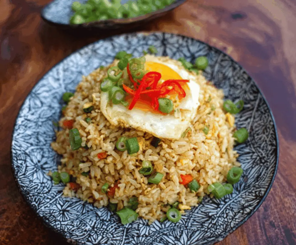 Delicious Japanese fried rice garnished with green onions and sesame seeds, served steaming hot.