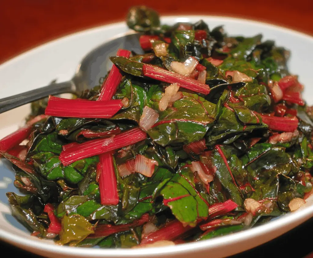 Delicious Swiss Chard with Onions and Garlic served on a plate, highlighting the vibrant green leafy vegetables and aromatic garlic.