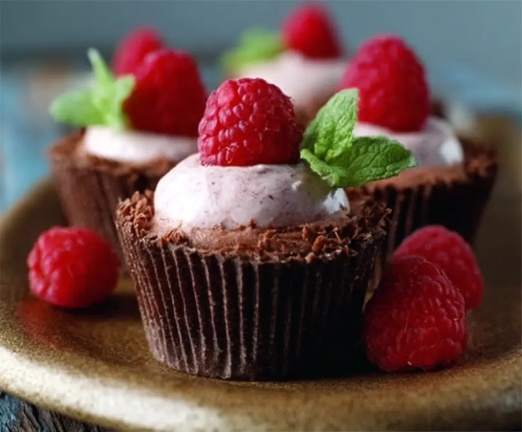 Delicious chocolate raspberry mousse cups garnished with fresh raspberries and chocolate shavings.