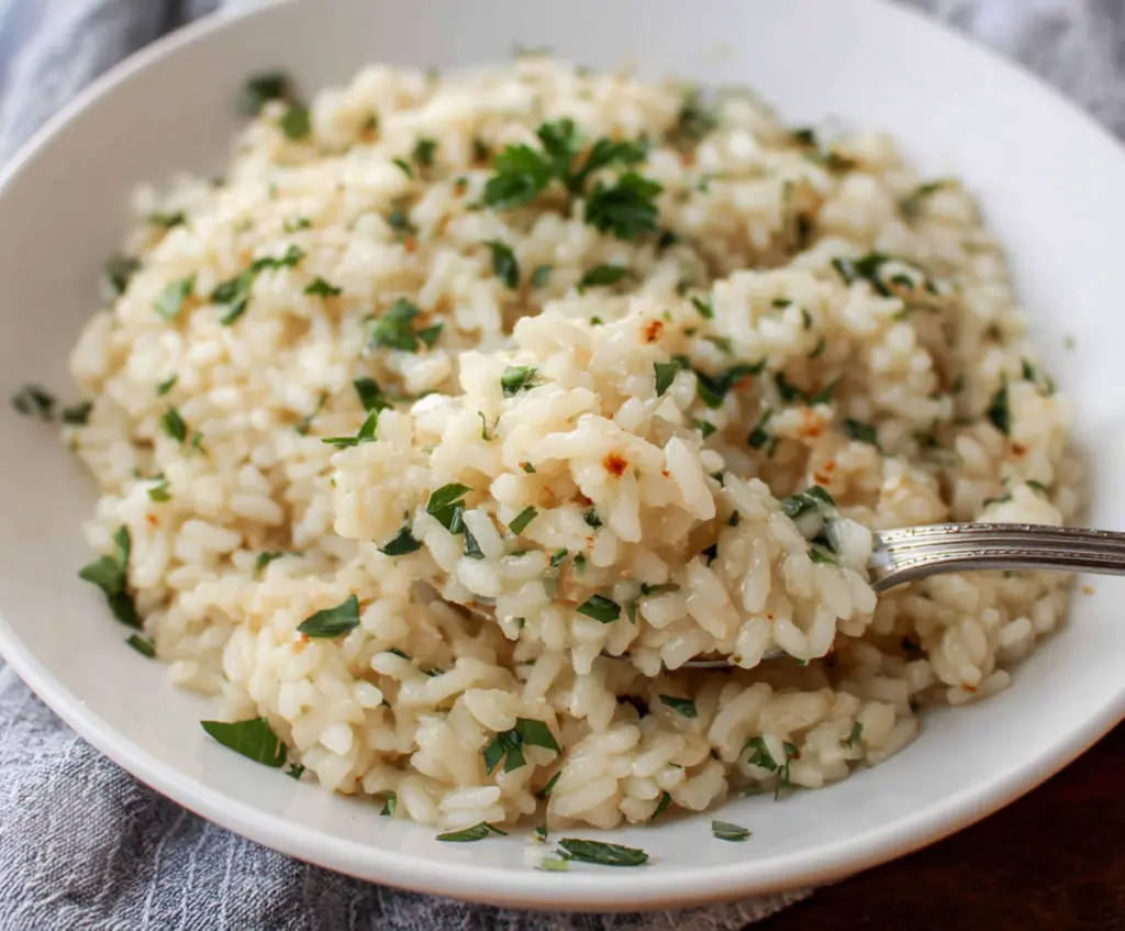 Creamy garlic Parmesan risotto served in a white bowl, garnished with fresh parsley for a flavorful Italian dish.