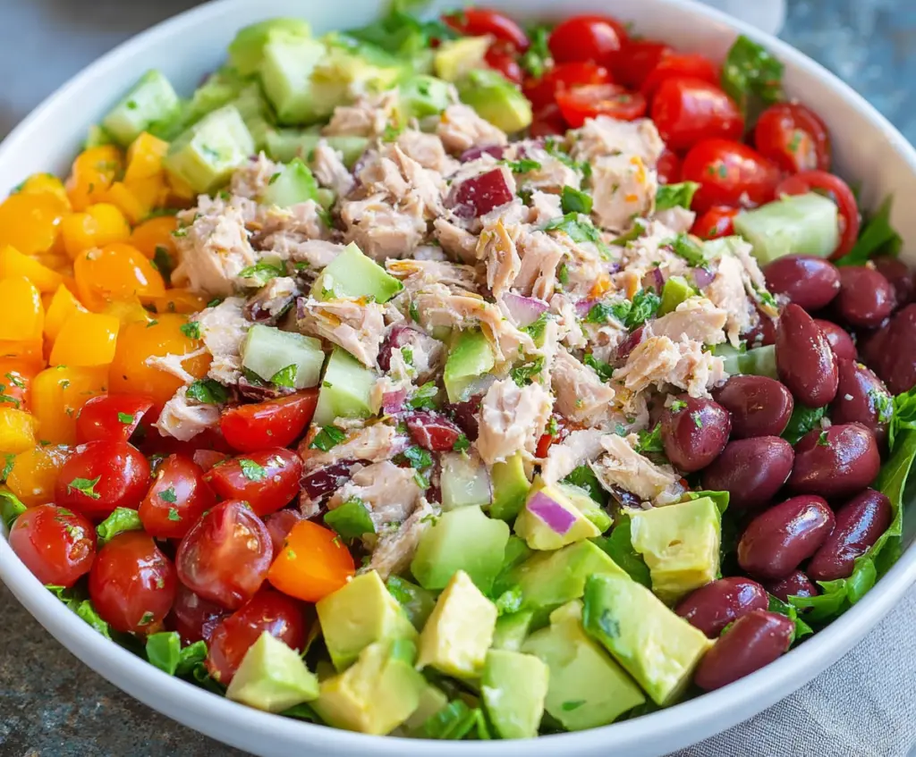 Healthy tuna salad in a bowl with fresh vegetables and lemon slices, perfect for a nutritious lunch.