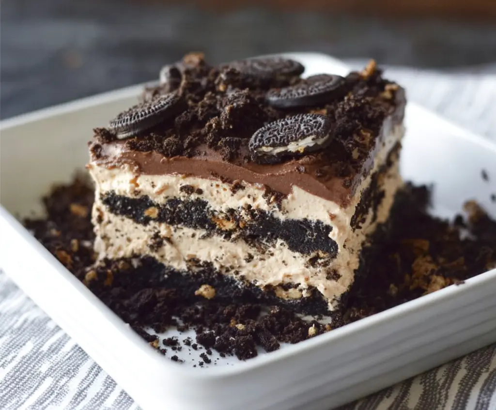 Delicious no bake Oreo icebox cake layered with whipped cream and crushed Oreos in a clear glass dish